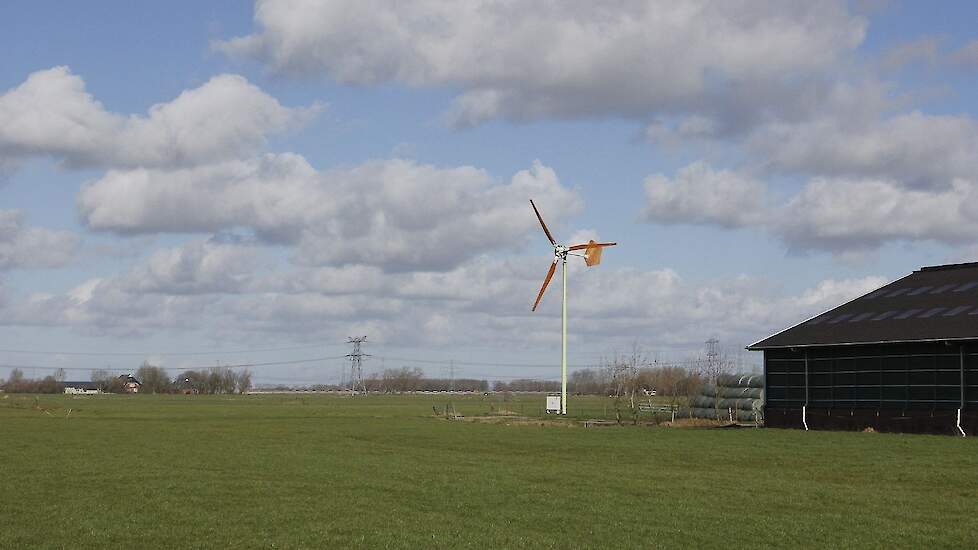 Afbeelding van een kleine windmolen op een boerenerf.