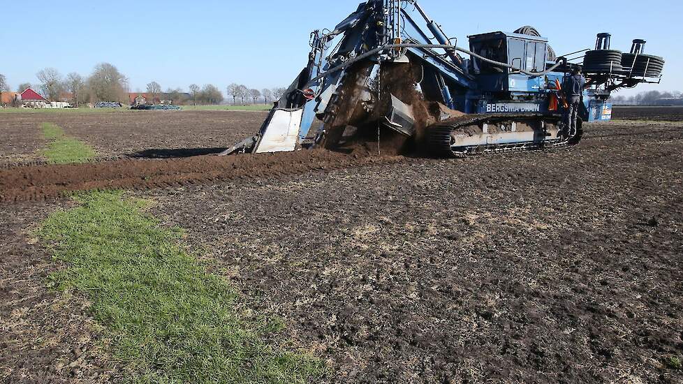 Bij de tweede werkgang wordt de sleuf gedicht met een, door het Friese bedrijf zelfgebouwd, schuifbord voor op de drainagemachine.