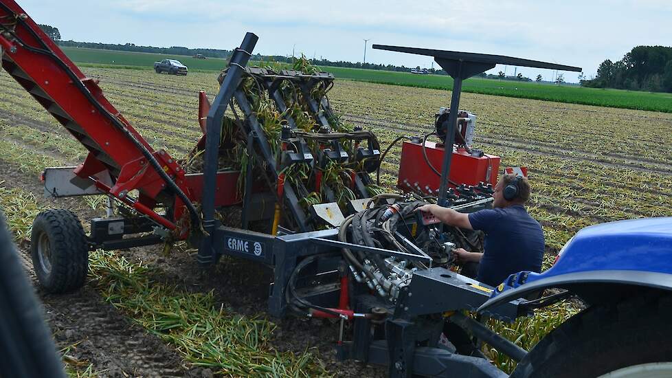 De man op de Erme-rooimachine houdt de rooibek in de gaten.