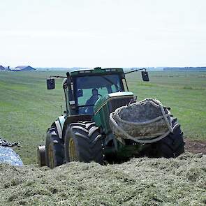 De rollen kuilplastic worden met de trekker de 5 meter hoge kuil opgetrokken.