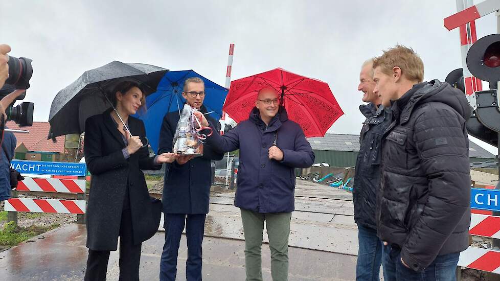 Vlnr: regiodirecteur Veenhof van ProRail, gedeputeerde De Vries, wethouder Rietman en melkveehouder Bokma met zijn zoon bij de pas beveiligde spoorwegovergang.