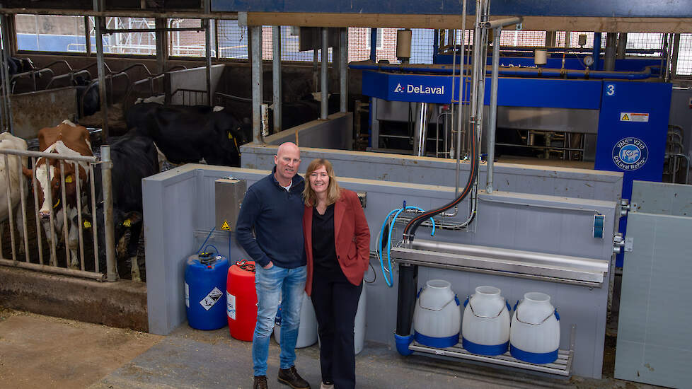 Roland en Janette Kooiker bij twee van de vier nieuwe melkrobots. Om de robots passend te maken in de bestaande stal, is er gekozen voor de zogeheten ‘kassaopstelling’.